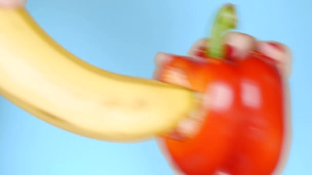 Gyümölcsök kék háttérben. friss gyümölcs banán és zöldség vörös édes paprika, Fun gyorsétterem-projekt közötti konfrontáció — Stock videók