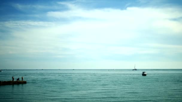 Silhouette di pescatori seduti sul vecchio molo. pesca al mare in una giornata di sole brillante — Video Stock