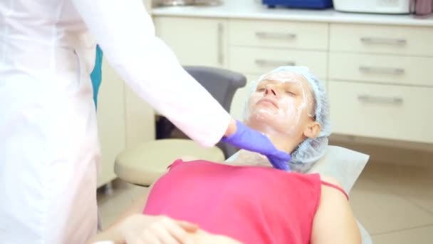 Koncept beauticijníka. Beauticijky položí smetanu na dívčí tvář — Stock video