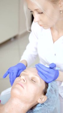 Kozmetolojist enjeksiyonlar yapar, bir kadının yüz ve boyun cilt kırışıklıkları sıkma ve yumuşatma için anti-aging prosedürleri. Dikey