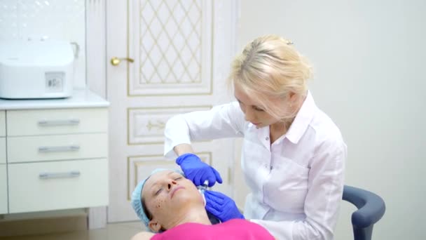 Kozmetolojist enjeksiyonlar yapar, bir kadının yüz ve boyun cilt kırışıklıkları sıkma ve yumuşatma için anti-aging prosedürleri. — Stok video