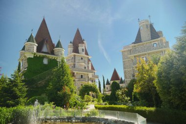 ayak küçük bir çeşme ile modern Viktorya tarzı lüks otel, açık güneşli havalarda mavi bir gökyüzüne karşı güzel bakımlı ağaçlar