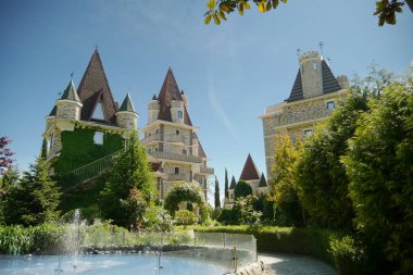 ayak küçük bir çeşme ile modern Viktorya tarzı lüks otel, açık güneşli havalarda mavi bir gökyüzüne karşı güzel bakımlı ağaçlar
