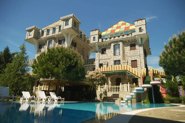 Moderno hotel di lusso in stile Tudor con una piscina blu ai piedi, con bellissimi alberi ben curati contro un cielo blu nel bel tempo soleggiato — Foto Stock