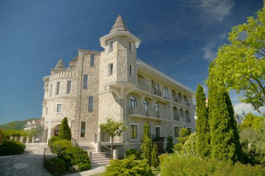 berrak güneşli havalarda mavi gökyüzüne karşı güzel bakımlı ağaçlar ile Viktorya tarzında modern lüks otel