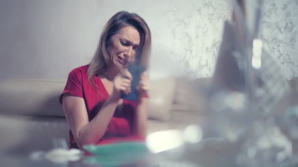 Ağlayan bir kadın iki romantik bir tarih için ayarlanmış bir masada evde birini bekliyor. telefonu kontrol eder — Stok video