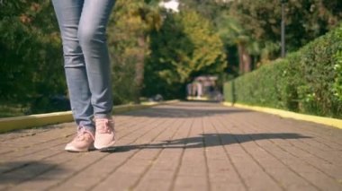 womens legs in jeans and sneakers are on a paved path