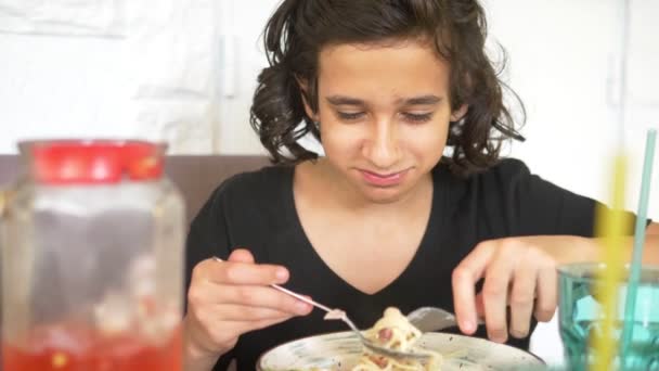 Jongen eten spaghetti in een restaurant met een vork en lepel — Stockvideo