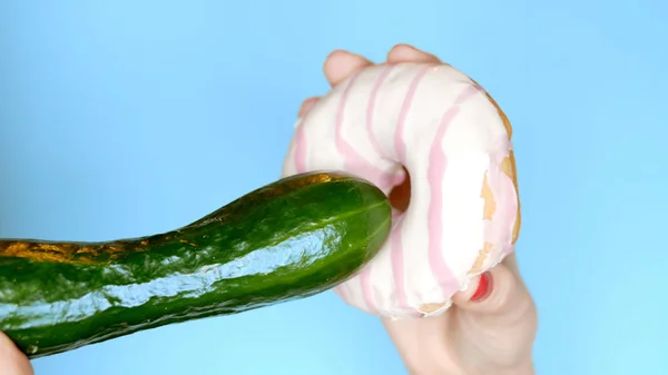 Begreppet hälsosam kost och diet. En gurka och en vit-rosa donut. Rolig snabbmat projekt — Stockfoto