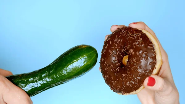The concept of a healthy diet and diet. chocolate donut against green cucumber. Fun fast food project — Stock Photo, Image
