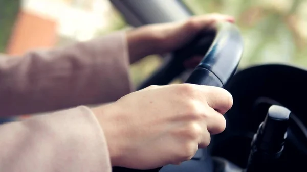 Les femmes mains dans un manteau rose sur le volant de la voiture. femme conduisant une voiture au printemps ou en automne — Photo