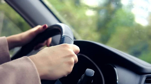 Les femmes mains dans un manteau rose sur le volant de la voiture. femme conduisant une voiture au printemps ou en automne — Photo