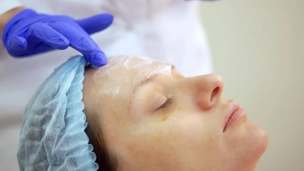 El concepto de esteticista. esteticista pone la crema en la cara de las niñas — Foto de Stock