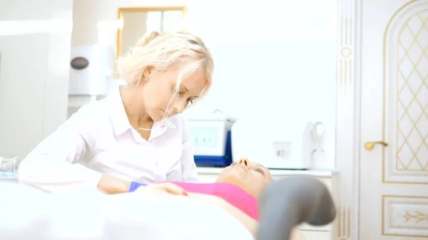 O cosmetologista faz injeções, procedimentos anti-envelhecimento para apertar e alisar rugas na pele do rosto e pescoço de uma mulher . — Fotografia de Stock