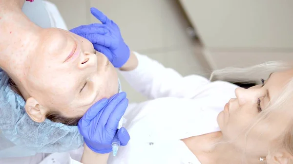 Kosmetolog membuat suntikan, prosedur anti-penuaan untuk mengencangkan dan merapikan keriput pada kulit wajah dan leher seorang wanita. secara vertikal — Stok Foto
