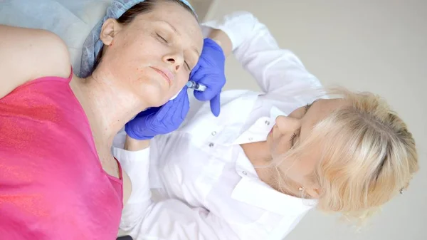 美感师进行注射、抗衰老程序，以收紧和抚平女性面部和颈部皮肤的皱纹。垂直 — 图库照片