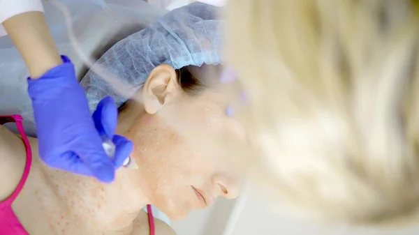 Kosmetolog robi zastrzyki, anty-aging procedury dokręcania i wygładzania zmarszczek na skórze twarzy i szyi kobiety. Pionowo — Zdjęcie stockowe