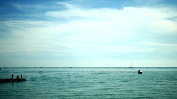 Silhouetten von Fischern, die auf dem alten Pier sitzen. Angeln am Meer an einem sonnigen Tag — Stockfoto