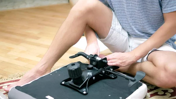 Un joven está montando una silla de oficina. El concepto de reparación y montaje de muebles — Foto de Stock