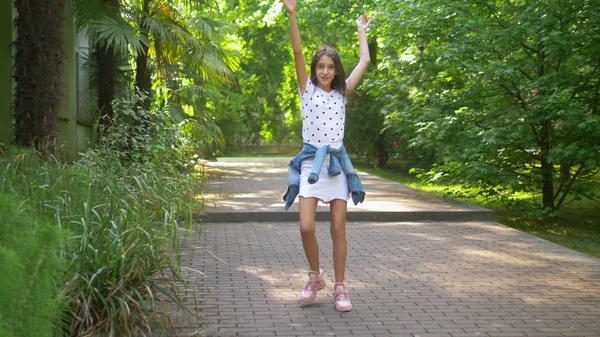 Hermosa chica delgada adolescente con pelo largo y oscuro bailando en el parque de verano entre el verde —  Fotos de Stock