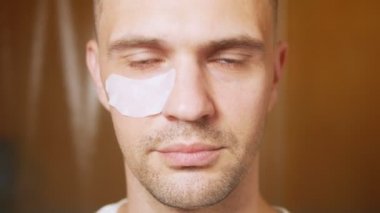 Banyoda, göz kapaklarının altında maskeli yakışıklı bir adamın portresi. Metroseksüel konsept, yüz bakımı