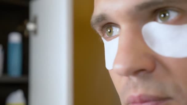 Portrait d'un bel homme avec un masque sous les paupières, dans la salle de bain. Concept métrosexuel, soins du visage — Video