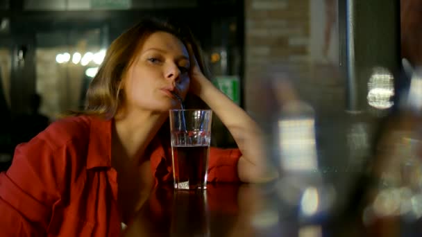 De cerca. retrato de una hermosa mujer sentada en un bar en un club nocturno solo y beber un cóctel. Espacio de texto — Vídeos de Stock