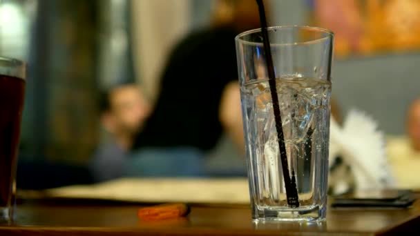 Friendly party concept. close-up of a glass with a cocktail on the background of blurry people — Stock Video