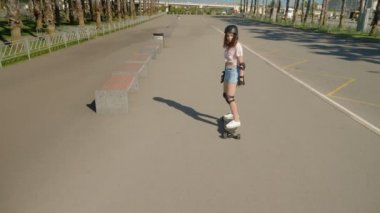 kız uzun palmiye ağaçları ile güzel bir parkta bir elektrikli kaykay sürme