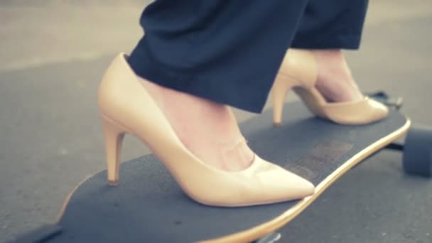 Primer plano. zapato beige para mujer en una tabla de skate negro. Mujer de negocios moderna en zapatos beige bombas, paseos en un tablero eléctrico a lo largo de una calle de la ciudad. El concepto de lograr la meta y el liderazgo — Vídeo de stock