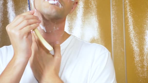 Portrait of a handsome man with a mask under the lower eyelid, which is shaved with a straight razor in the bathroom. Metrosexual concept — Stock Video