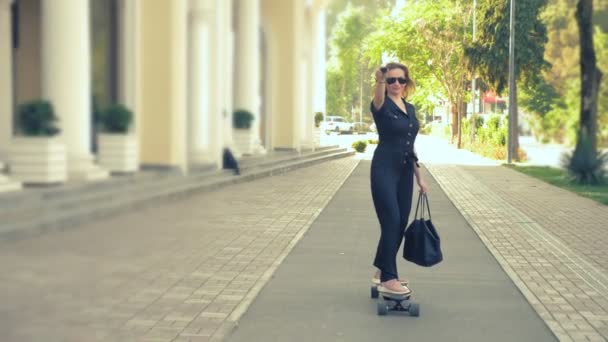 분홍색 운동화, 선글라스, 검은 색 가방을 입고 도시 거리를 따라 전기 보드를 타고 있는 현대 의 비즈니스 여성은 한 쪽 팔을 앞으로 뻗어 있는 슈퍼 남자를 묘사합니다. 컨셉은 — 비디오