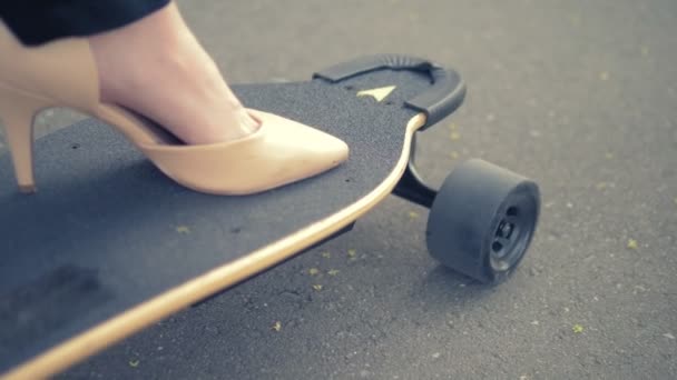 Närbild. Womens beige sko på en svart Skate Board. Modern affärskvinna i beige pumpar skor, Rider på en elektrisk bräda längs en stadsgata. Konceptet att uppnå målet och ledarskap — Stockvideo