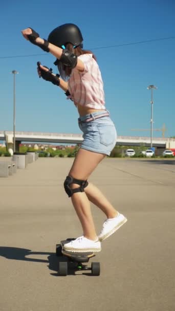 Menina montando um skate elétrico em um belo parque com palmeiras altas, vídeo vertical — Vídeo de Stock