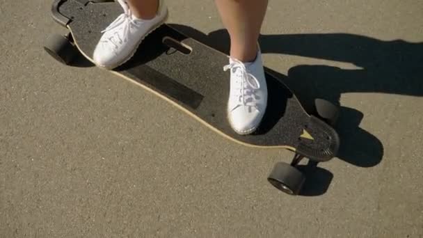 Flicka rider en elektrisk skateboard i en vacker park med höga palmer, ben närbild — Stockvideo