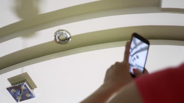 Daño al agua. concepto de inundación del apartamento y el seguro de propiedad. una mujer toma una foto en el teléfono mientras gotea agua del techo de su apartamento — Vídeo de stock