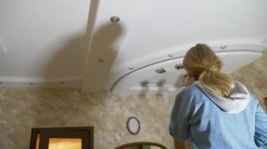 Su hasarı. Daire ve mülkiyet sigortası sel kavramı. dairede tavana su damlar ve bir korku bir kadın telefon yardım çağırır