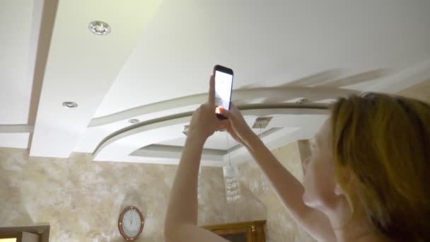 Wasserschaden. Konzept der Überflutung der Wohnung und Sachversicherung. eine Frau macht ein Foto am Telefon, während Wasser von der Decke ihrer Wohnung tropft — Stockvideo