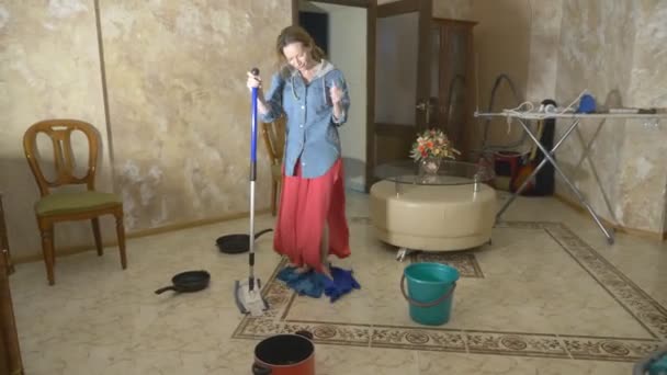 Wasserschaden. Konzept der Überflutung der Wohnung und Sachversicherung. Wasser tropft von der Decke in der Wohnung, und eine Frau wischt mit Lumpen und einem Wischmopp Wasser vom Boden. — Stockvideo