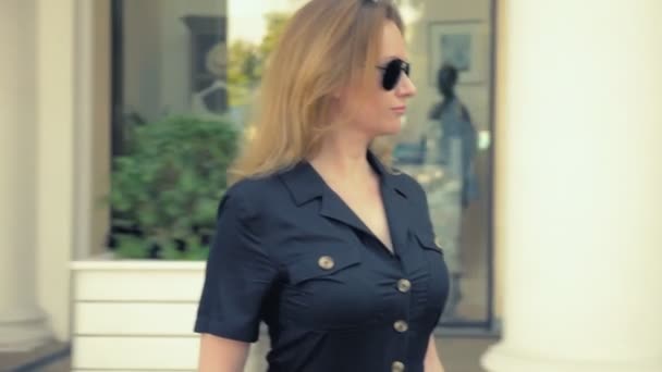 Сучасна ділова жінка в чорному комбінезоні, сонцезахисні окуляри, що їздять на електричній дошці вздовж міської вулиці — стокове відео