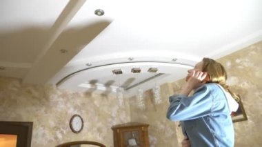 Su hasarı. Daire ve mülkiyet sigortası sel kavramı. dairede tavana su damlar ve bir korku bir kadın telefon yardım çağırır