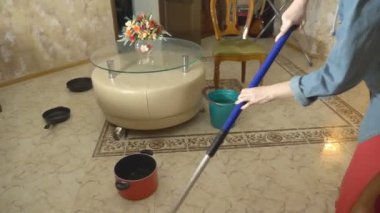 Su hasarı. Daire ve mülkiyet sigortası sel kavramı. dairede tavana su damlar ve bir kadın paçaları ile yerden su mendiller ve bir paspas