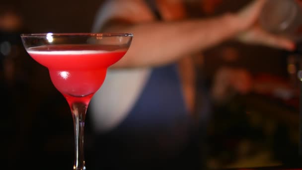 Zavřít. Sklenička s Martini v ostrosti na pozadí rozmazaný podkladový barman, který dělá koktejl — Stock video