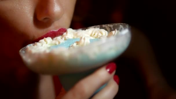 Sexy vrouw met rode lippenstift op haar lippen is het drinken van een cocktail uit een glas Margarita. Close-up lippen, crème blijft op de lippen, meisje likt zijn tong. — Stockvideo