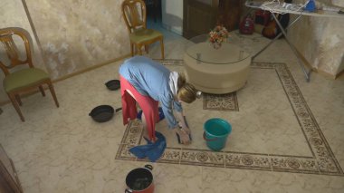 Su hasarı. Daire ve mülkiyet sigortası sel kavramı. dairede tavana su damlar ve bir kadın paçaları ile yerden su mendiller ve bir paspas