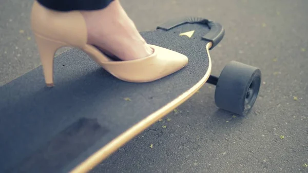 close-up. womens beige shoe on a black skate board. Modern business woman in beige pumps shoes, rides on an electric board along a city street. The concept of achieving the goal and leadership