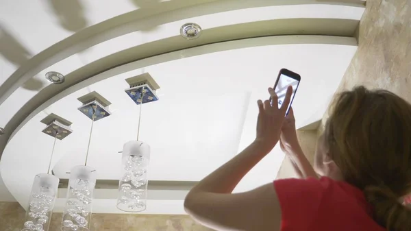 Water schade. concept van overstromingen het appartement en onroerend goed verzekering. een vrouw neemt een foto op de telefoon als water druipt van het plafond van haar appartement — Stockfoto