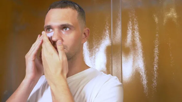 Portret van een knappe man met een masker onder de oogleden, in de badkamer. Metrosexual concept, gezichtsverzorging — Stockfoto