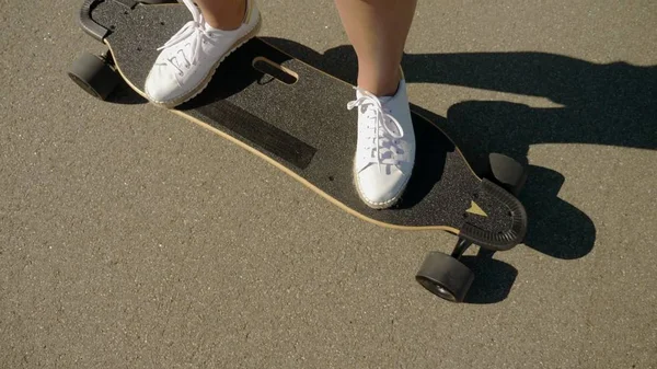 Dívka jezdila na elektrickém skateboard v krásném parku s vysokými palmami a nohama zblízka — Stock fotografie