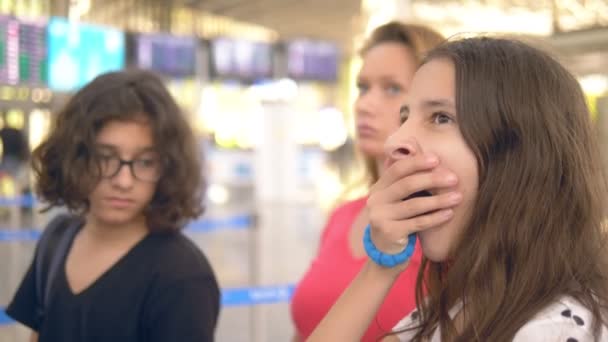 Έννοια του τουρισμού, των διακοπών και των ανταλλαγών. Μια γυναίκα και δύο έφηβοι, ένα αγόρι και ένα κορίτσι, στέκονται στο αεροδρόμιο στο γραφείο εισιτηρίων για το check-in. — Αρχείο Βίντεο